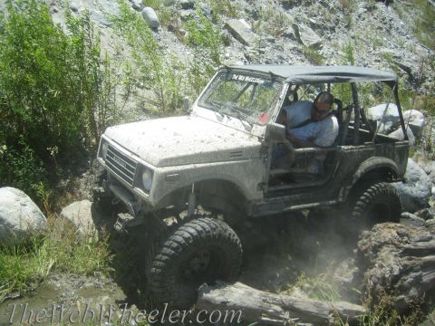 1987 Suzuki Samurai - Suzuki Samurai tackling an off-road trail, kicking up dust and mud.
