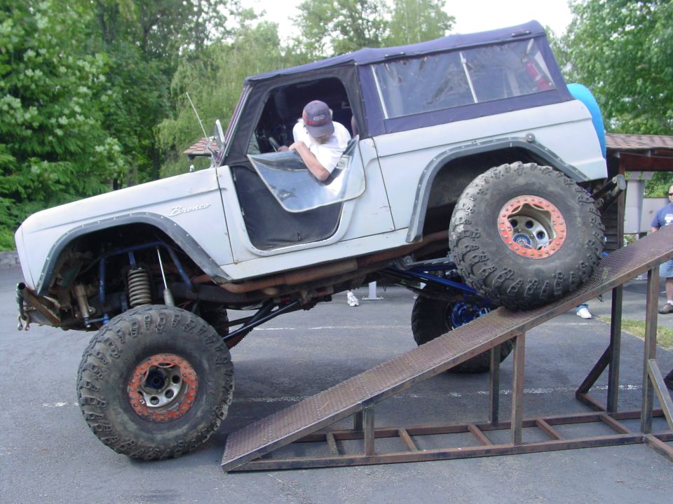 1973 Ford Bronco with lifted suspension and large tires on a metal ramp
