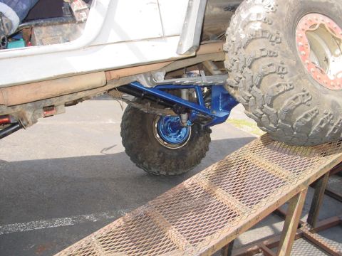 1973 Ford Bronco - Close-up of the undercarriage and suspension of a modified off-road vehicle on a metal ramp.