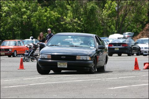 2001 Mercury Grand Marquis - A black Chevrolet sedan navigates an autocross course with other vehicles visible in the background.