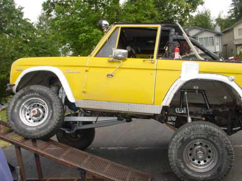 1973 Ford Bronco - This yellow 1973 Ford Bronco features a lifted suspension and aggressive off-road tires, shown here ascending a metal ramp.