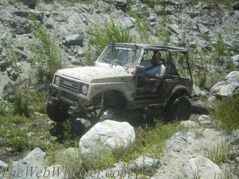 1987 Suzuki Samurai - Suzuki Samurai tackling a challenging off-road course with a driver behind the wheel.