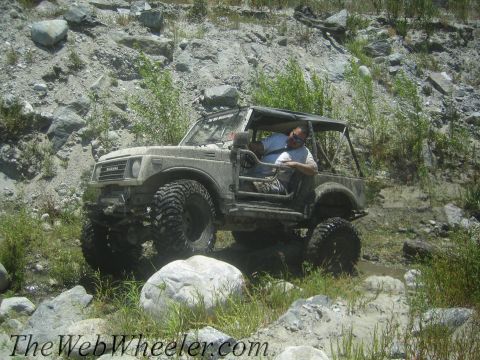 1987 Suzuki Samurai - A modified Suzuki Samurai navigates a challenging off-road course with a driver behind the wheel.