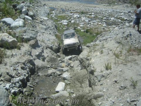 1987 Suzuki Samurai - A white 1987 Suzuki Samurai navigates a challenging off-road course in a dry riverbed.