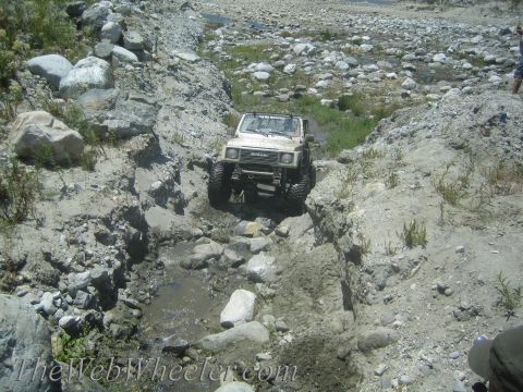 1987 Suzuki Samurai - Suzuki Samurai tackling a challenging off-road course with rocky obstacles and water.