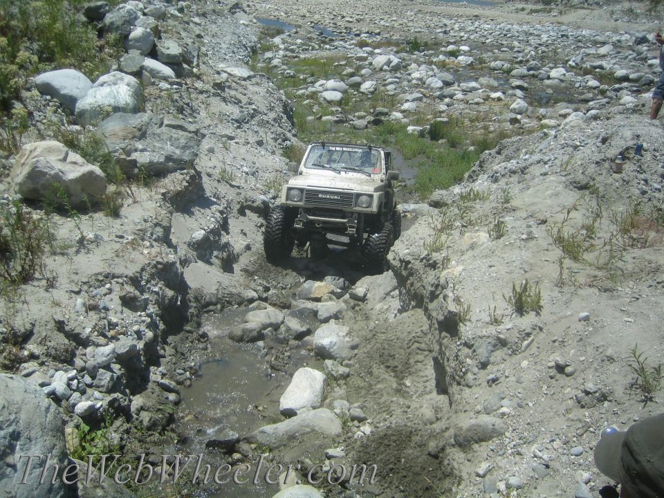 1987 Suzuki Samurai navigating a rocky, wet terrain