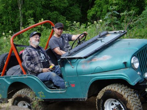 2000 Ford E350 - Two men ride in a teal Jeep as it navigates an off-road trail.