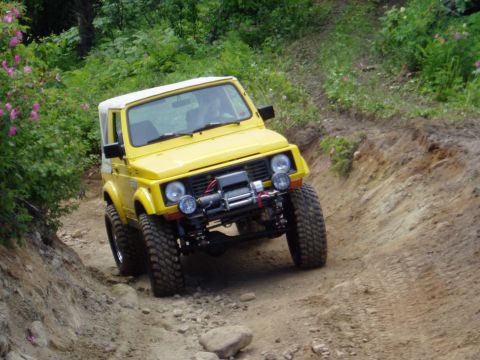 2000 Ford E350 - Yellow off-road vehicle navigating a challenging dirt trail with steep inclines.