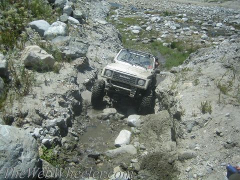 1987 Suzuki Samurai - A Suzuki Samurai tackles a challenging off-road trail, navigating through water and rocks.