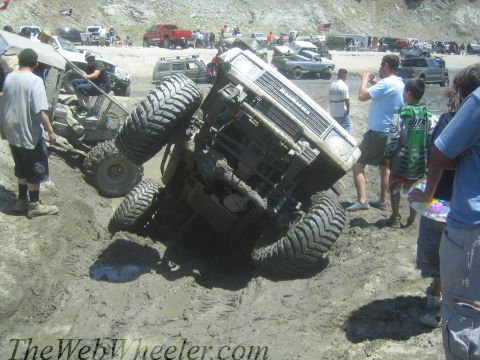 1987 Suzuki Samurai - An off-road vehicle is stuck in a mud pit with spectators watching.