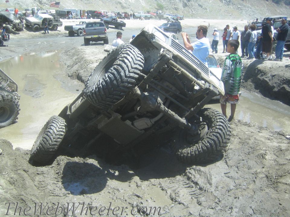 Off-road vehicle overturned in mud pit with spectators watching