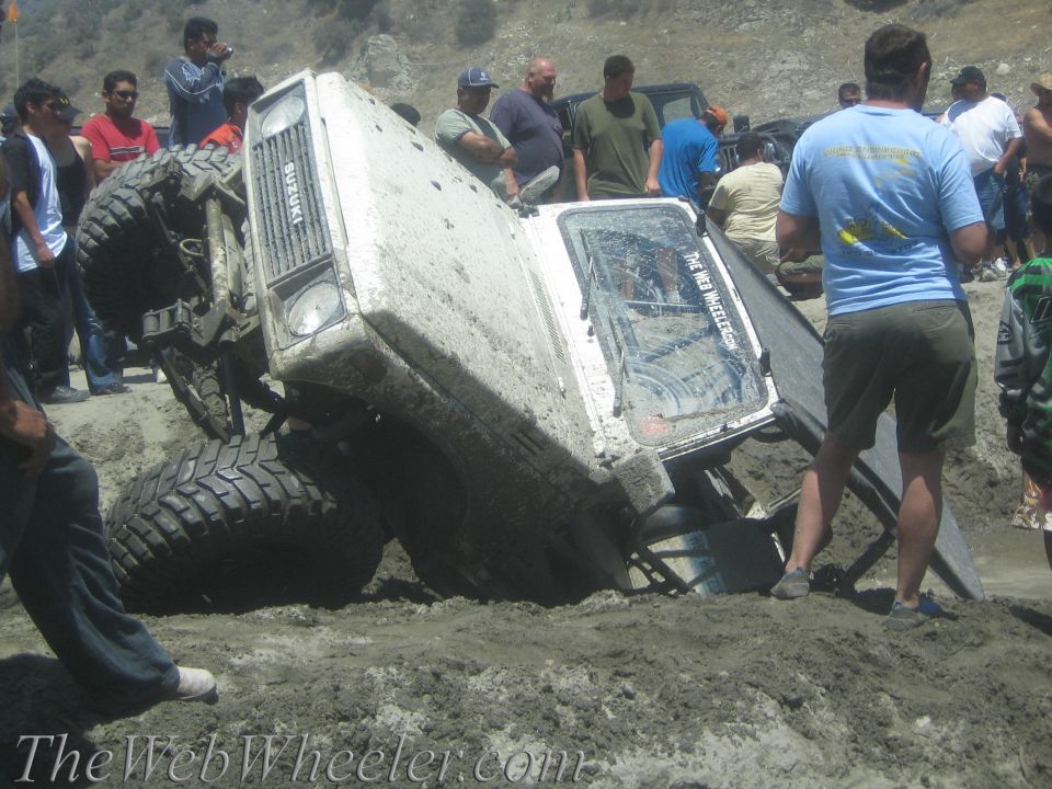 Suzuki Samurai tipped over in mud with people watching