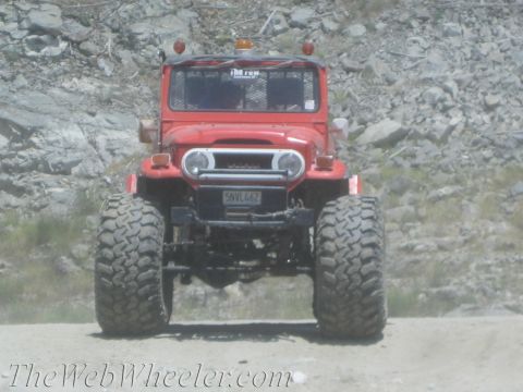 1987 Suzuki Samurai - This red off-road vehicle, likely a Toyota Land Cruiser FJ40, is seen from the front with oversized tires.