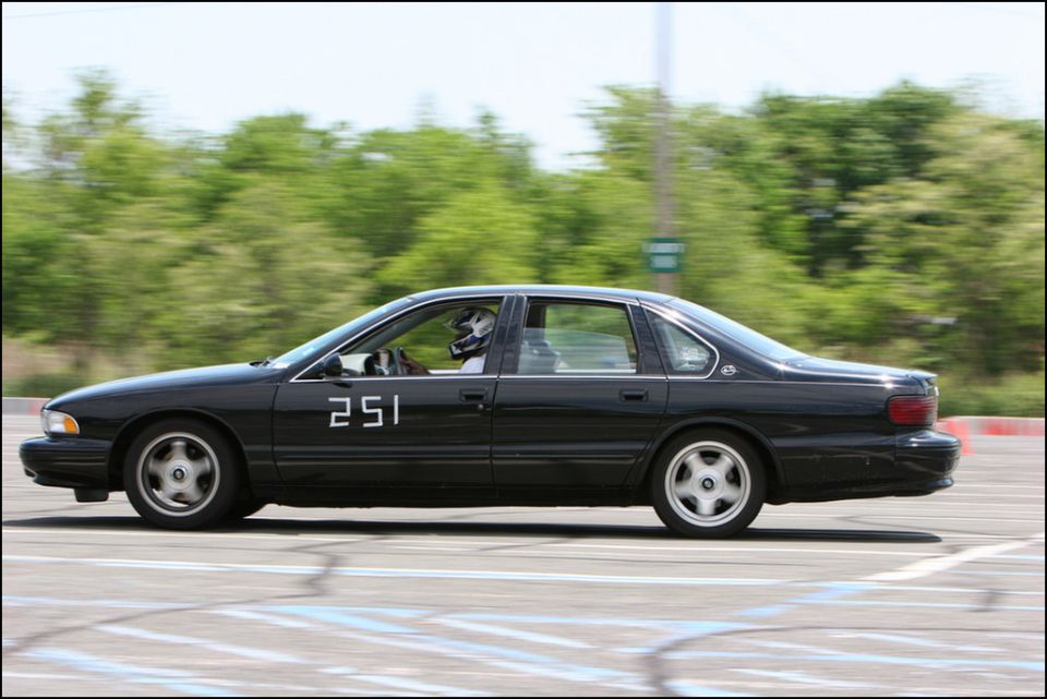 Black sedan with racing number 251 on the door, driver wearing a helmet, on a race track