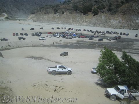 1987 Suzuki Samurai - A large group of off-road vehicles gathered in a dry riverbed, with a white pickup truck in the foreground.