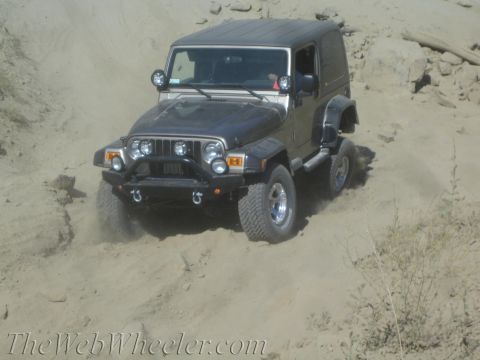 1987 Suzuki Samurai - A gray Jeep Wrangler navigates a sandy off-road path.