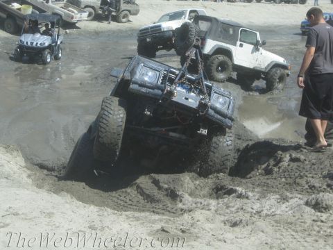 1987 Suzuki Samurai - A 1987 Suzuki Samurai struggles in the mud, with its front-right wheel submerged and its engine visible.