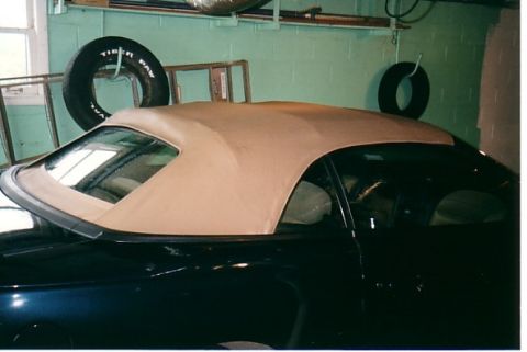 1991 Ford LTD Crown Victoria - A car with a tan convertible top is parked in a garage with tires hanging on the wall.