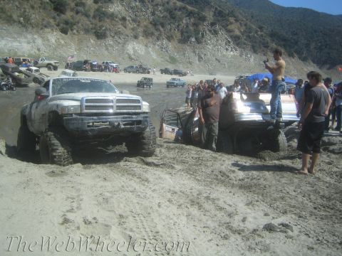 1987 Suzuki Samurai - Several off-road vehicles are gathered on a sandy terrain with a hillside in the background.