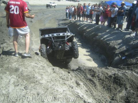 1987 Suzuki Samurai - A group of spectators watches as an off-road vehicle navigates a muddy trench.