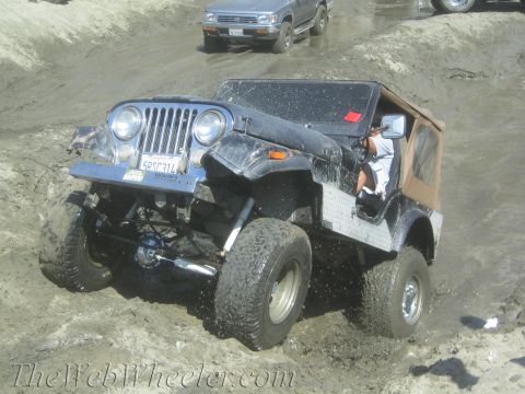 1987 Suzuki Samurai - Jeep CJ-7 navigates a muddy trail with another vehicle following.