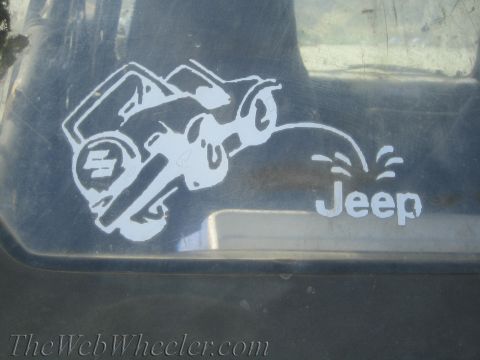 1987 Suzuki Samurai - A humorous sticker shows a Suzuki Samurai urinating on a Jeep logo, implying dominance.