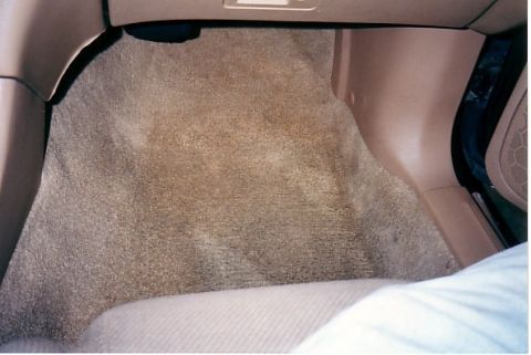 1991 Ford LTD Crown Victoria - The tan carpeted floor of a vehicle's interior is visible, with a watermark reading 'SUPERMOTORS' in the lower right corner.