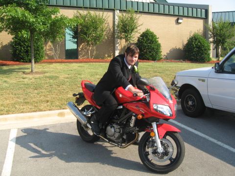 1988 Ford Bronco - A person in a suit rides a red sport motorcycle next to a white truck.