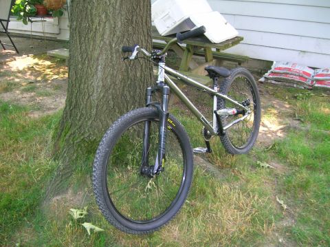 1997 Ford Probe - A bicycle is parked outdoors next to a tree with a picnic table and bags of material in the background.