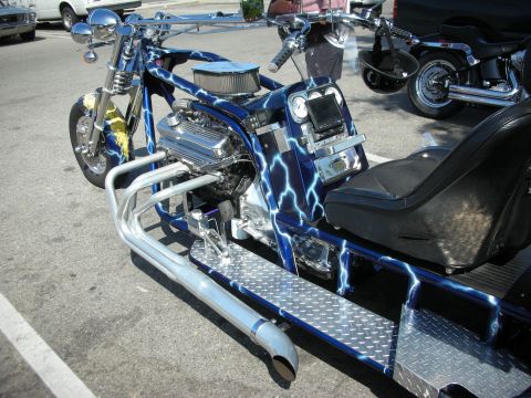 1998 Ford Crown Victoria - A custom trike with a striking blue lightning paint scheme and a powerful V8 engine is parked next to another motorcycle.