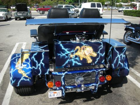 1998 Ford Crown Victoria - Custom trike with lightning graphics and lion artwork parked in a lot, other vehicles visible.