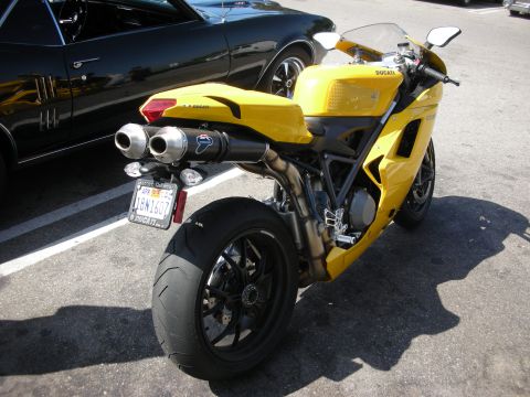 1998 Ford Crown Victoria - A yellow Ducati motorcycle is parked next to a black car.