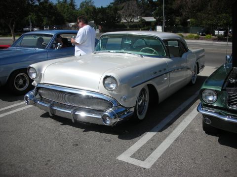 1998 Ford Crown Victoria - A white 1950s Buick is parked in a lot with other vehicles.