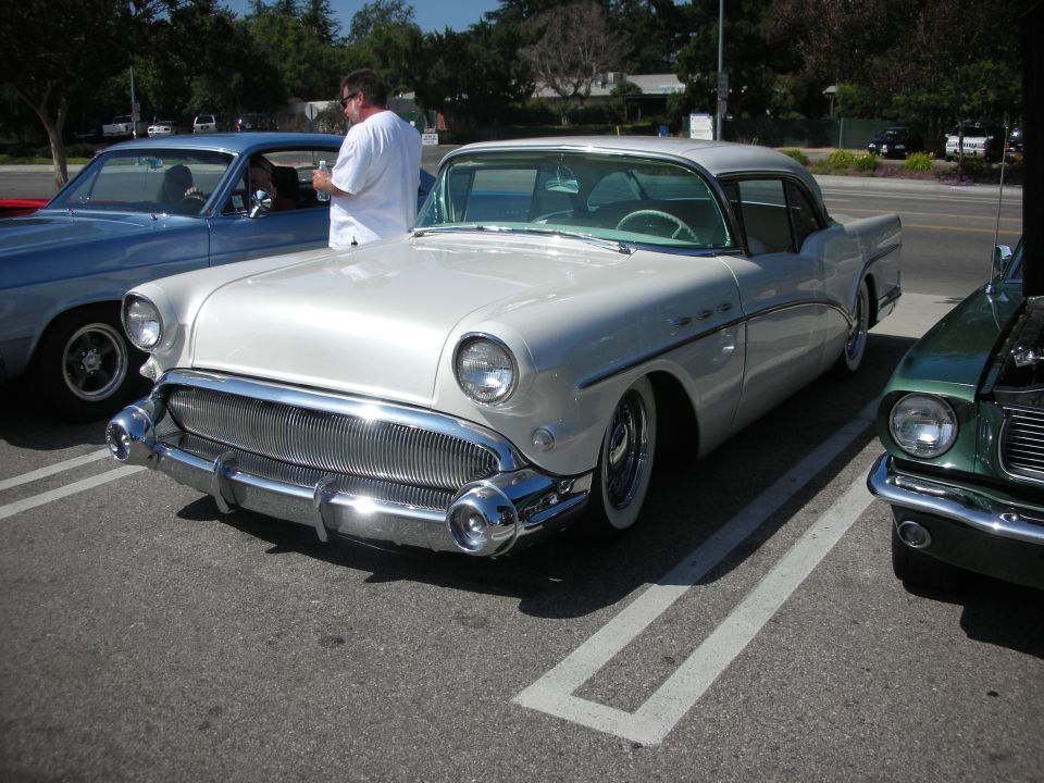 White 1950s Buick parked next to a blue car and a green car
