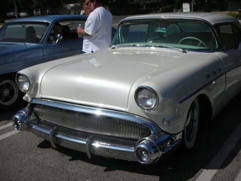 1998 Ford Crown Victoria - A white 1955 Buick Special is parked next to a blue car, with a man standing between them.