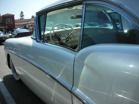 1998 Ford Crown Victoria - A light-colored coupe from the 1950s is seen from the side, revealing its chrome accents and interior details.