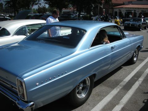 1998 Ford Crown Victoria - A light blue classic car, possibly a 1966 Ford Fairlane, is parked in a lot with other vehicles.