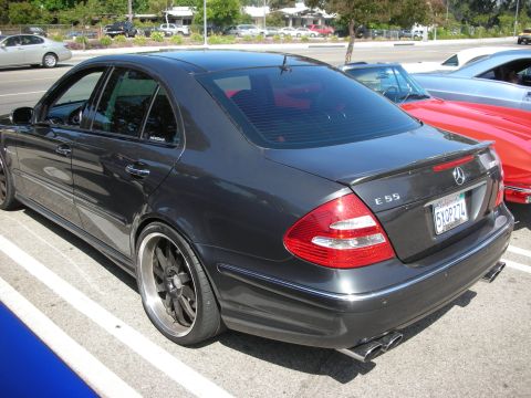 1998 Ford Crown Victoria - This Mercedes-Benz E55 AMG sedan, seen from the rear, features custom wheels and quad exhaust pipes, indicating a performance-oriented mode…