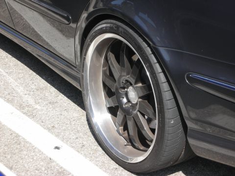 1998 Ford Crown Victoria - Close-up of a car's wheel and fender, showing custom rims and tires.