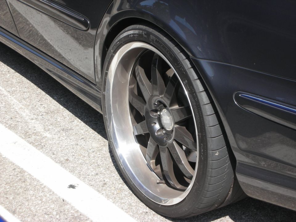 Dark car with custom multi-spoke wheels and low-profile tires, close-up on front wheel well