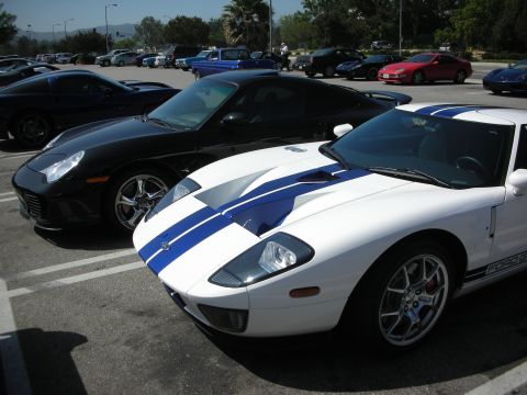 1998 Ford Crown Victoria - A white Ford GT with blue stripes is parked in a lot next to other vehicles.