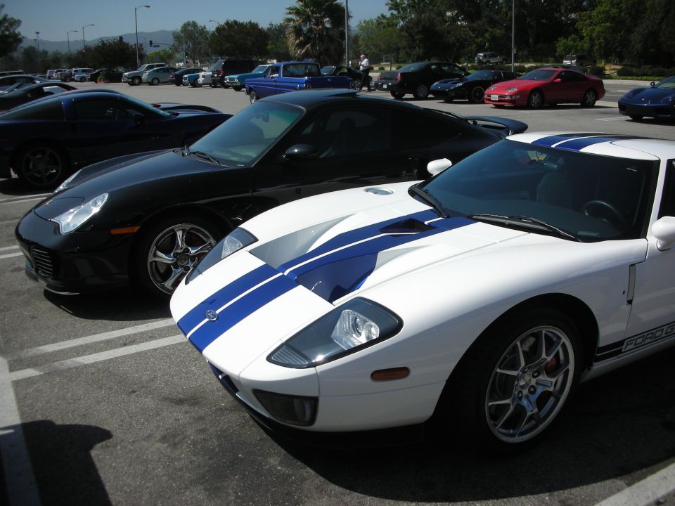 White Ford GT with blue racing stripes parked in a lot, front quarter view
