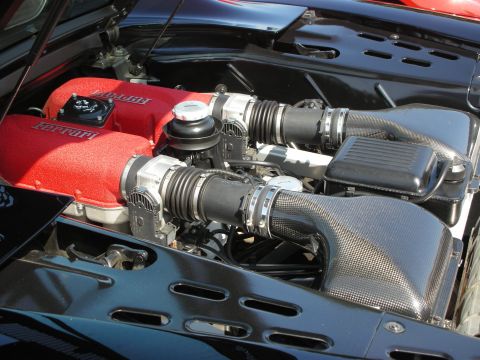 1998 Ford Crown Victoria - Close-up view of a Ferrari engine, highlighting the red air intake covers and carbon fiber intake components.