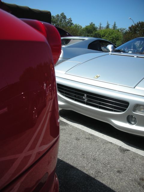 1998 Ford Crown Victoria - Two Ferraris parked side-by-side, one in red and one in silver, under a clear blue sky.
