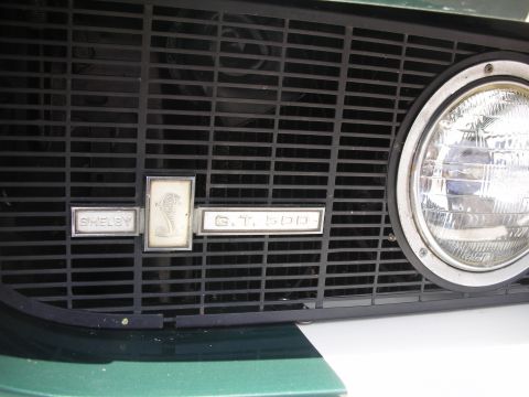 1998 Ford Crown Victoria - Close-up of a Shelby GT500 emblem on the grille of a classic car.
