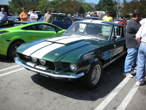 1998 Ford Crown Victoria - A classic Mustang and a modern sports car are displayed at an outdoor car meet.
