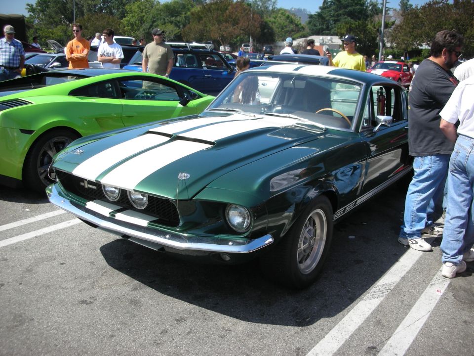 Green 1967 Ford Mustang Shelby GT500 with white stripes, parked next to a bright green Lamborghini