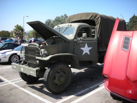 1998 Ford Crown Victoria - Military truck and a red car at a car meet.