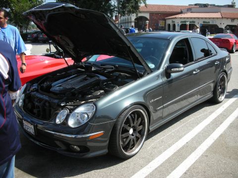 1998 Ford Crown Victoria - Dark gray Mercedes-Benz E-Class sedan with hood open, parked at an outdoor event.