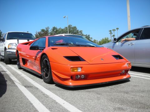 1998 Ford Crown Victoria - Orange Lamborghini Diablo with black wheels and body kit is parked in a lot.